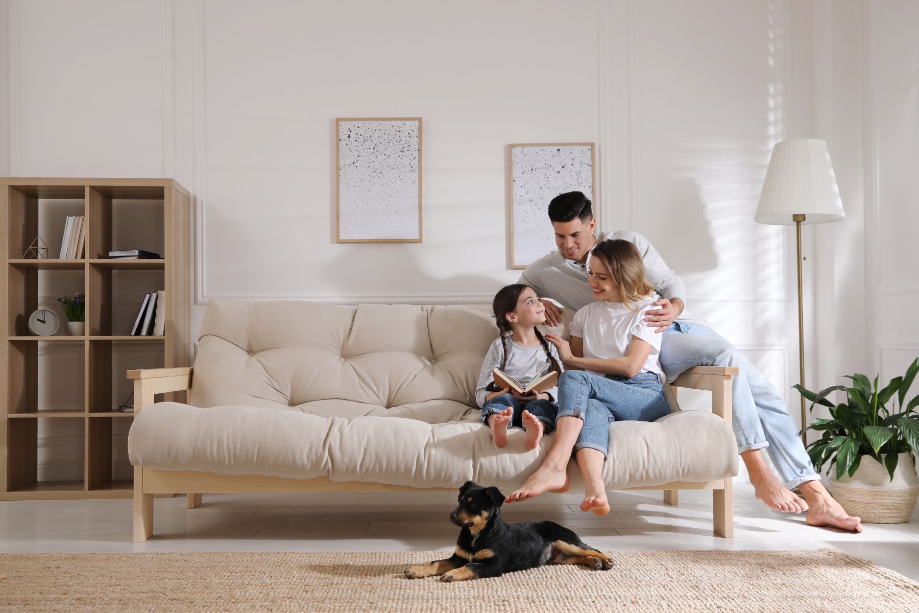 Family with child and dog relaxing on beige futon in bright living room