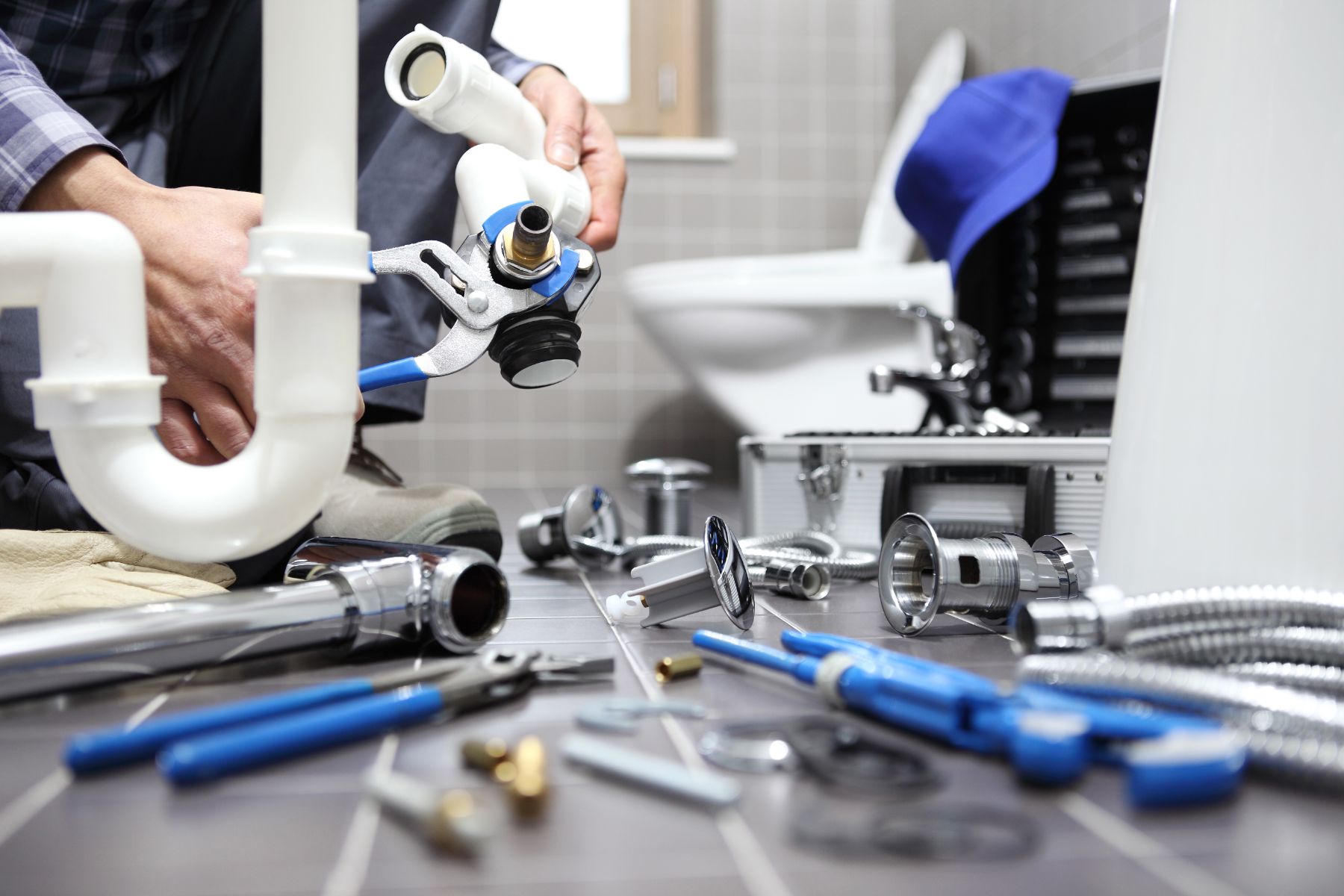 Plumber holding water shut-off valve with tools and pipes on workbench