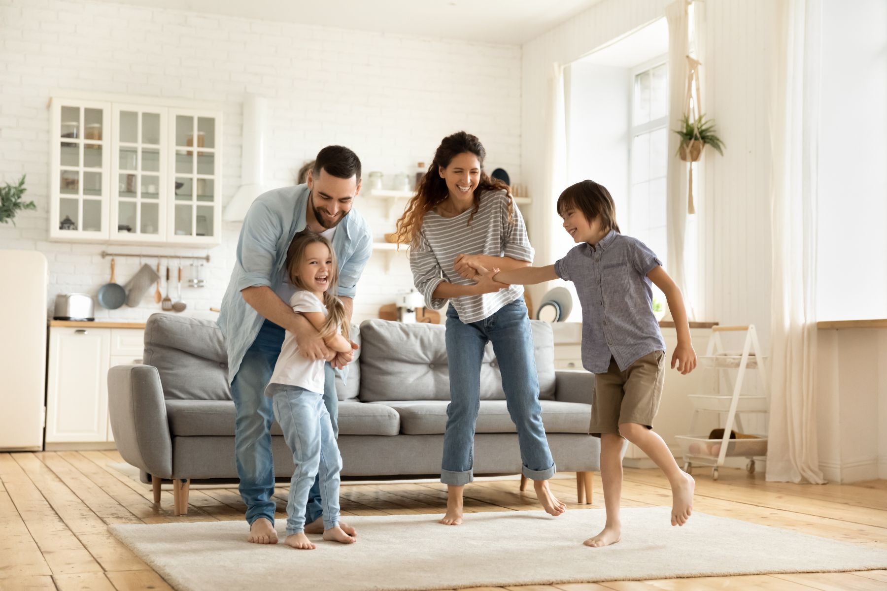 Happy family playing together in bright modern living room with kitchen
